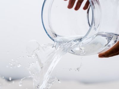 person holding clear glass jar with water