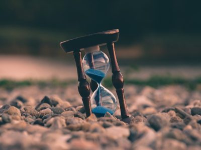 selective focus photo of brown and blue hourglass on stones