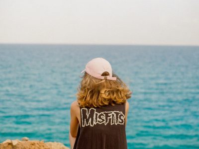 person wearing sleeveless top facing the ocean during day