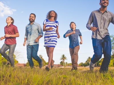 people running on grassfield under blue skies at daytime