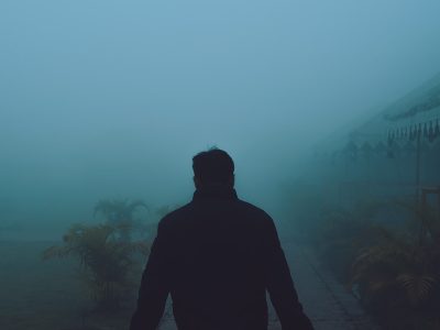 a man standing in the fog with his back to the camera