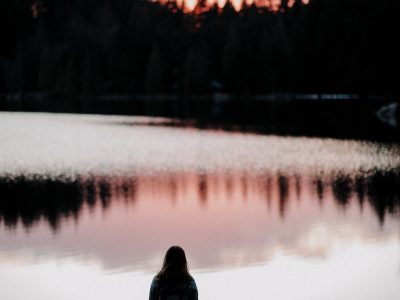 silhouette photography of woman standing beside body of water