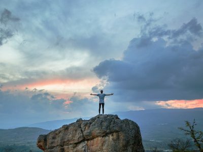 man standing on top of rock mountain during golden hour