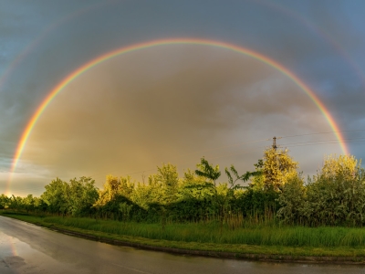 two rainbows in the sky over a road